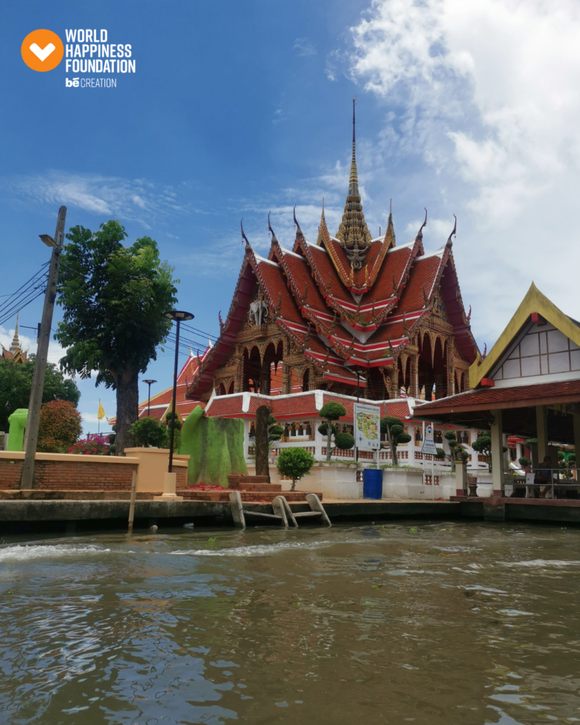 Riverside Thai temple with a golden spire and tiered red roofs on the Chao Phraya in Bangkok