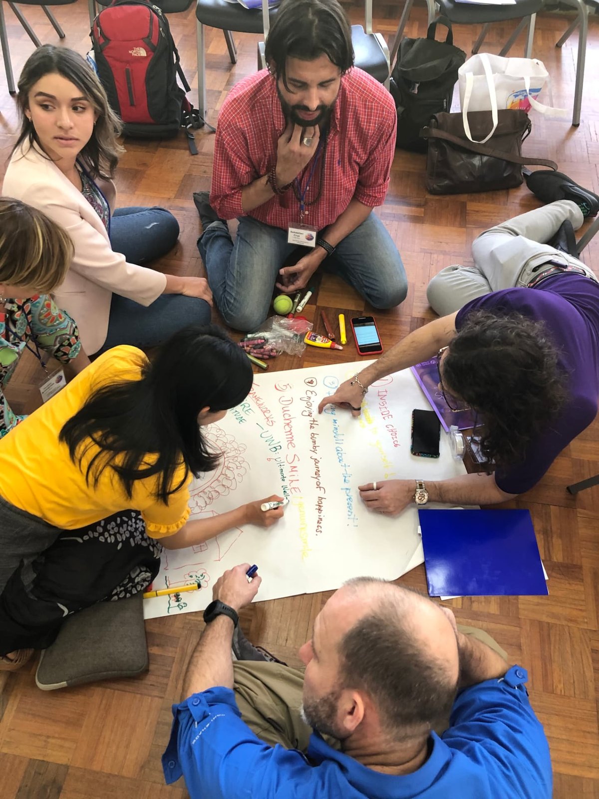 Participants kneeling on the floor drawing a shared map on a large sheet of paper