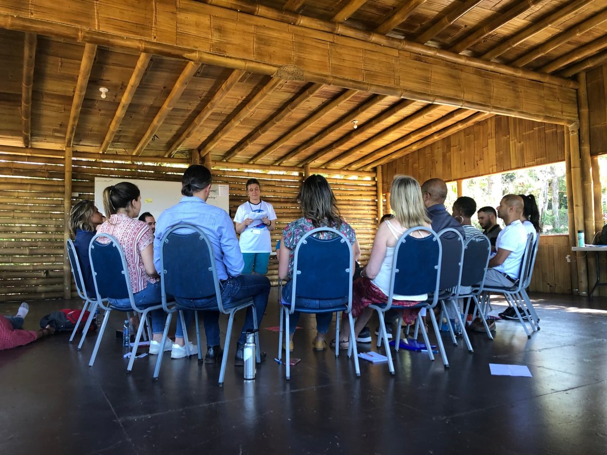 A small group in a close circle of chairs listening to a facilitator