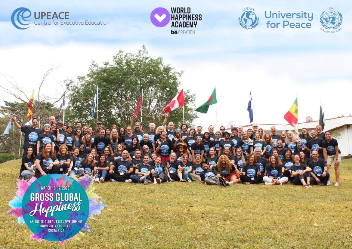 Large group photograph of Gross Global Happiness summit participants with flags behind them