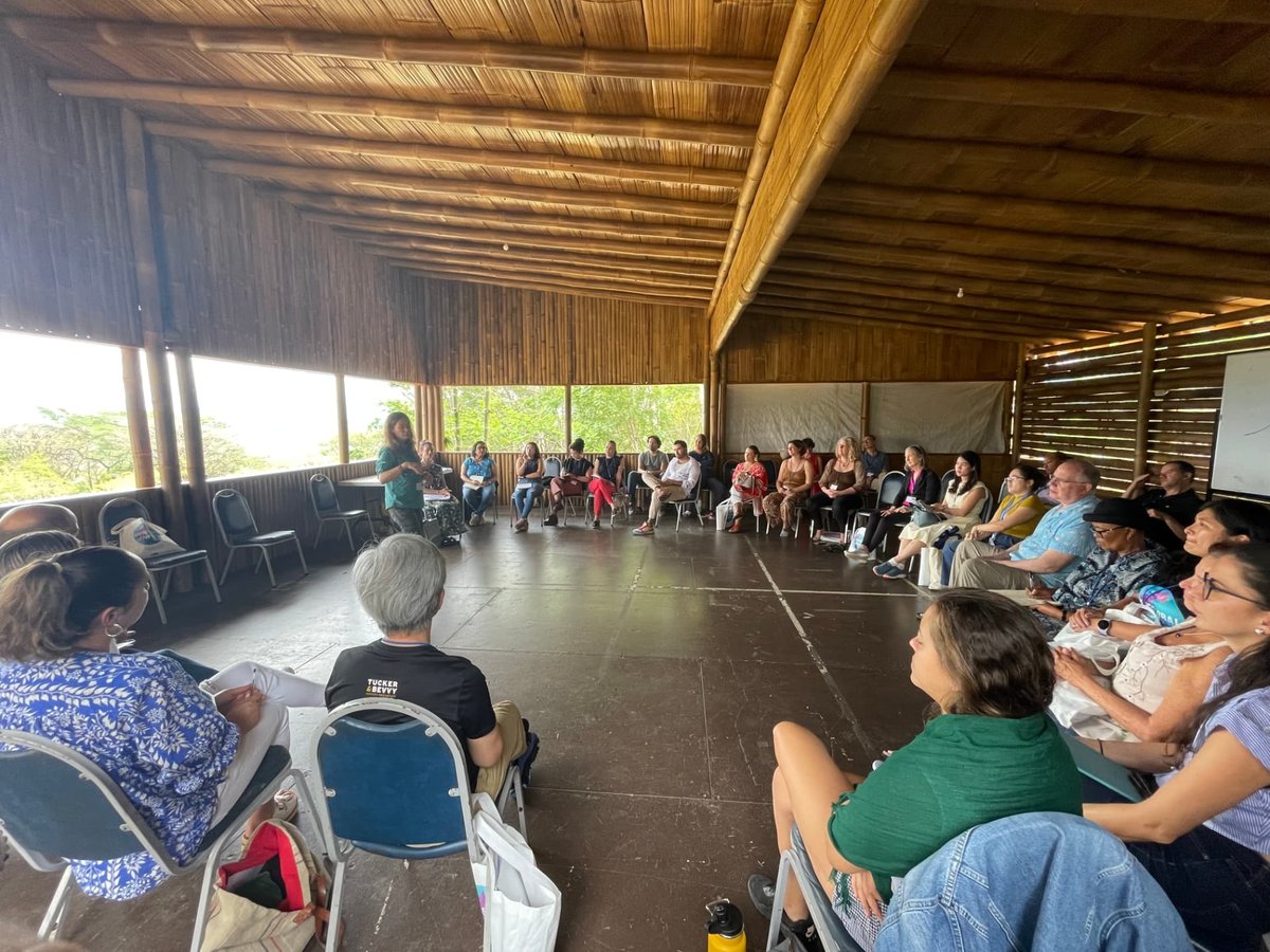 Participants seated in a wide open circle in a bamboo pavilion