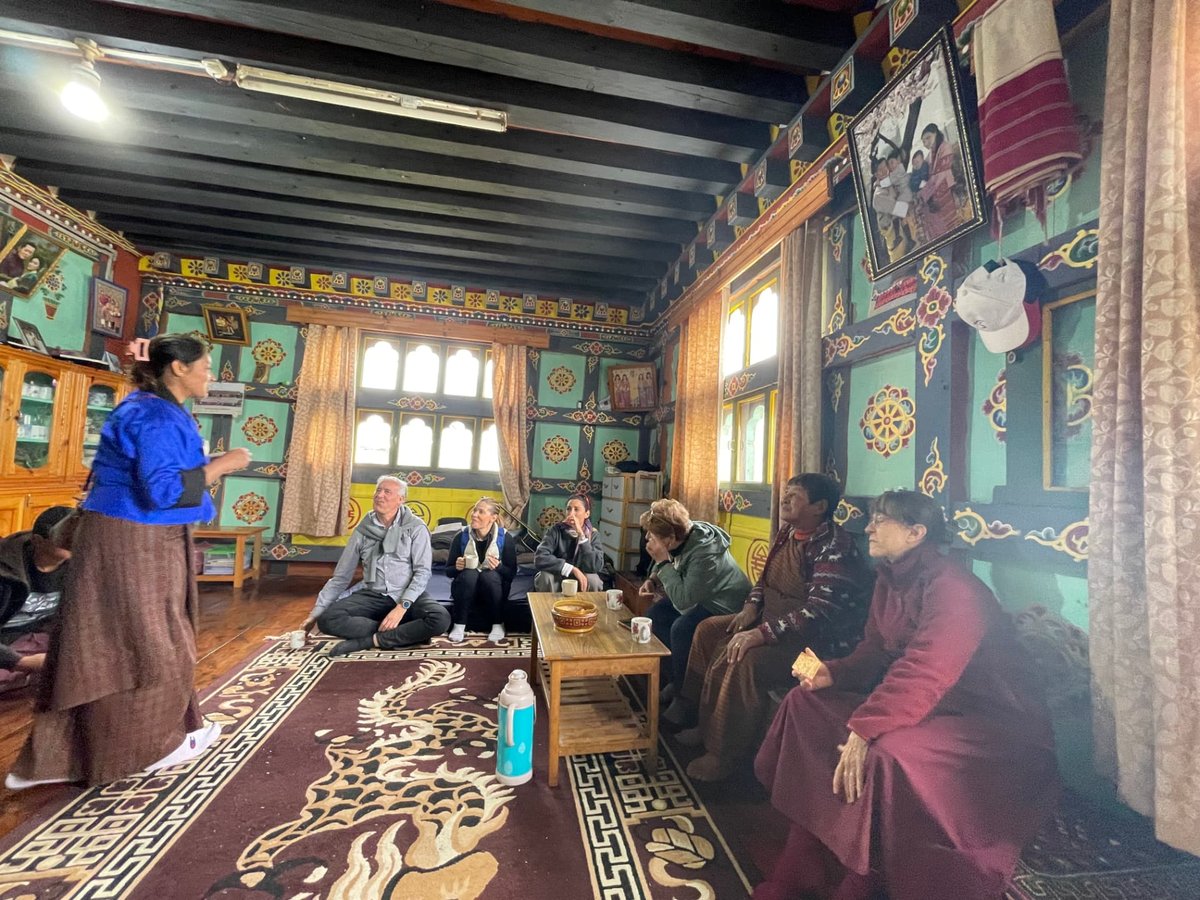 Visitors and hosts sharing tea seated on the floor of a traditional Bhutanese home