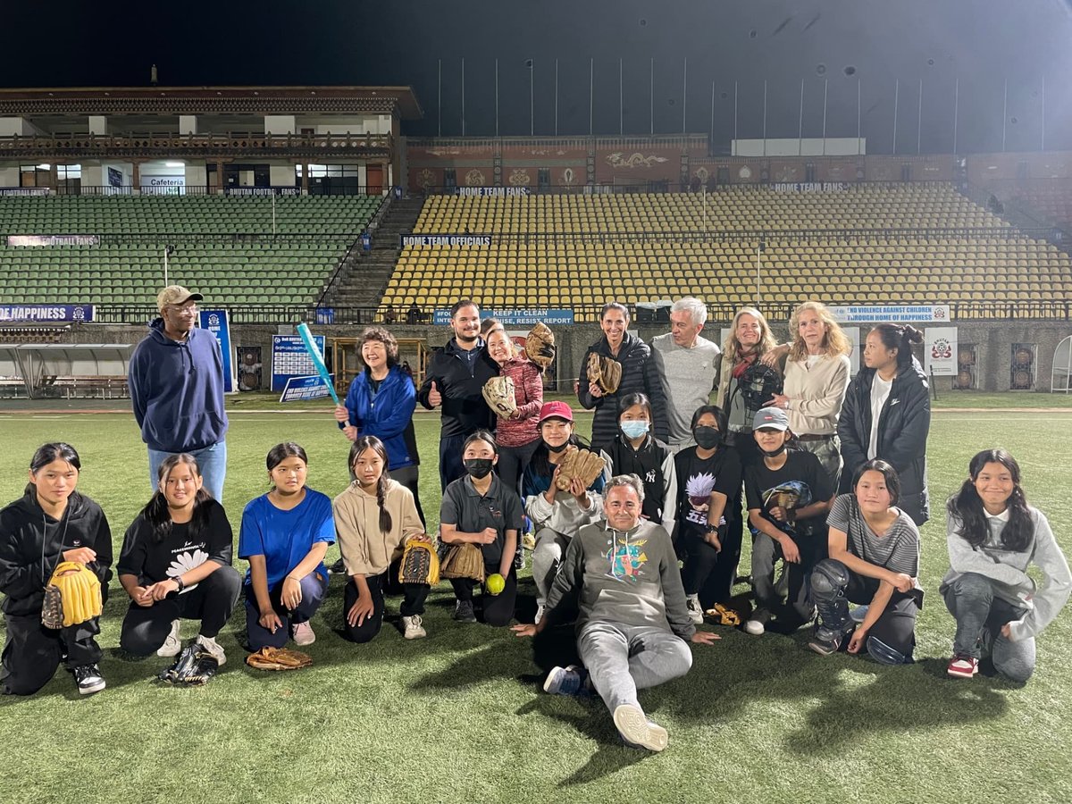 Group photograph of a youth sports team with Foundation members on a floodlit pitch in Bhutan